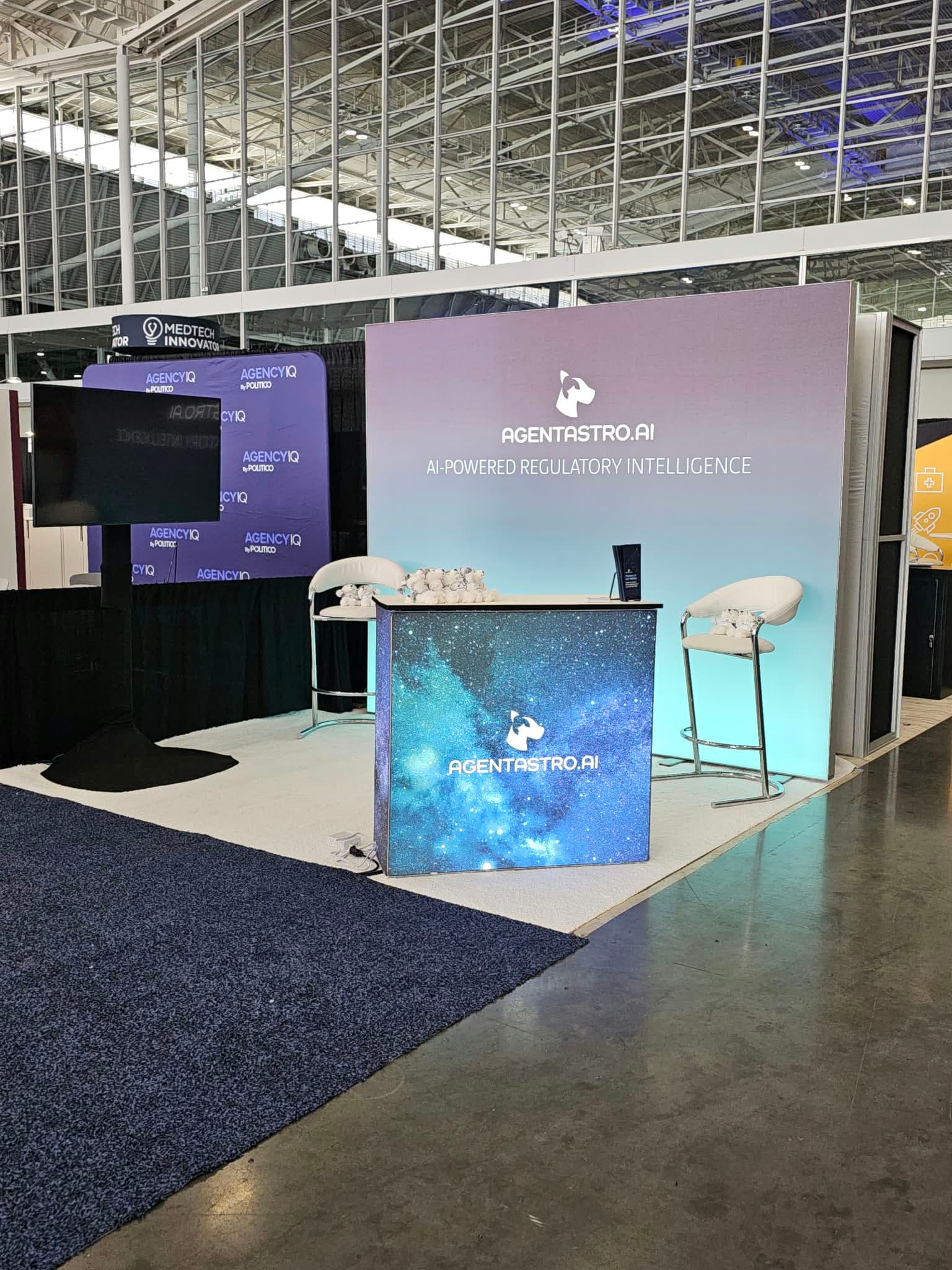 The Agent Astro booth at The MedTech Conference in Boston, with its AI-Powered Regulatory Intelligence backdrop and starfield counter.